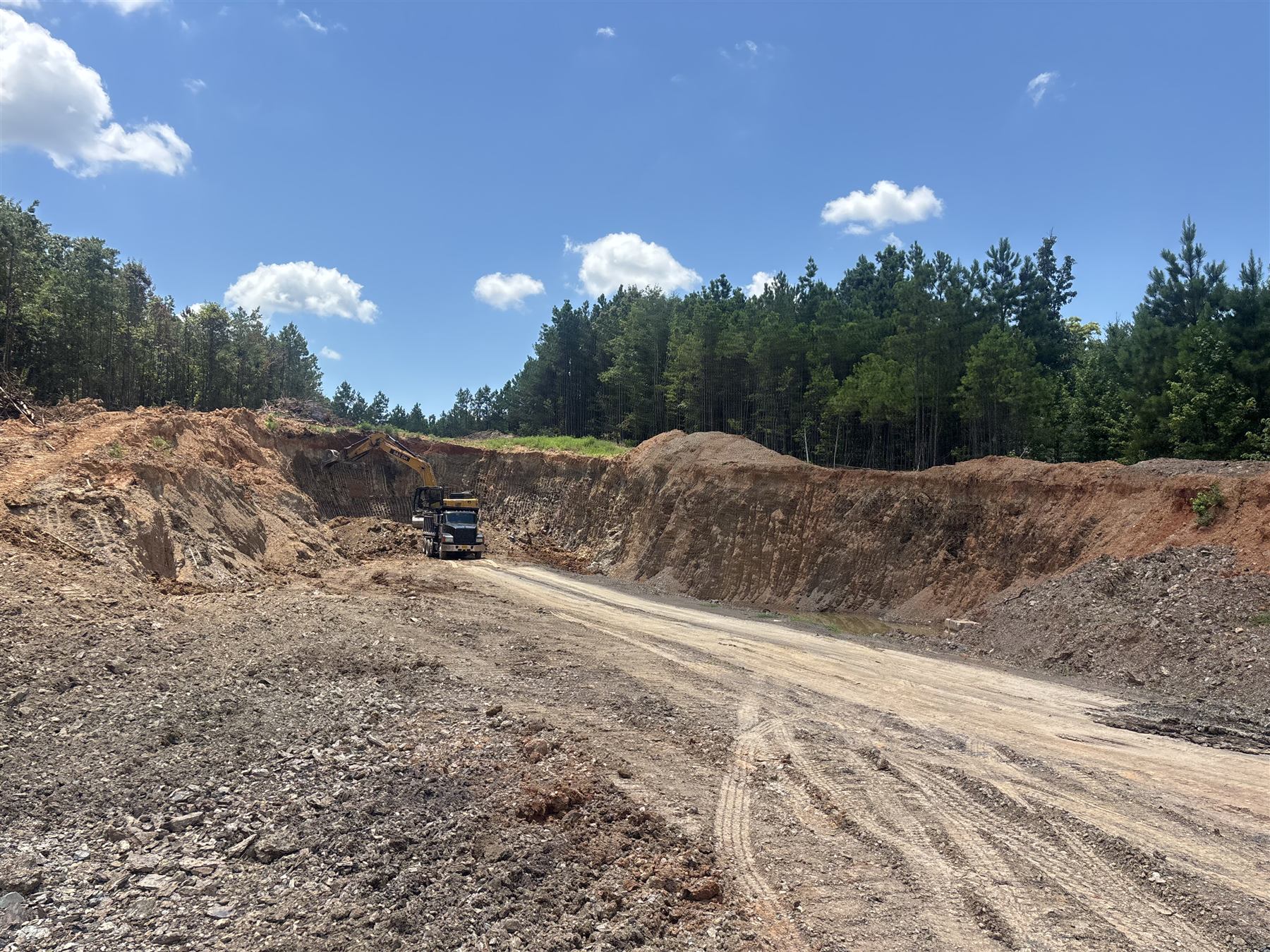 C&C excavator loading a dump truck at a dirt pit
